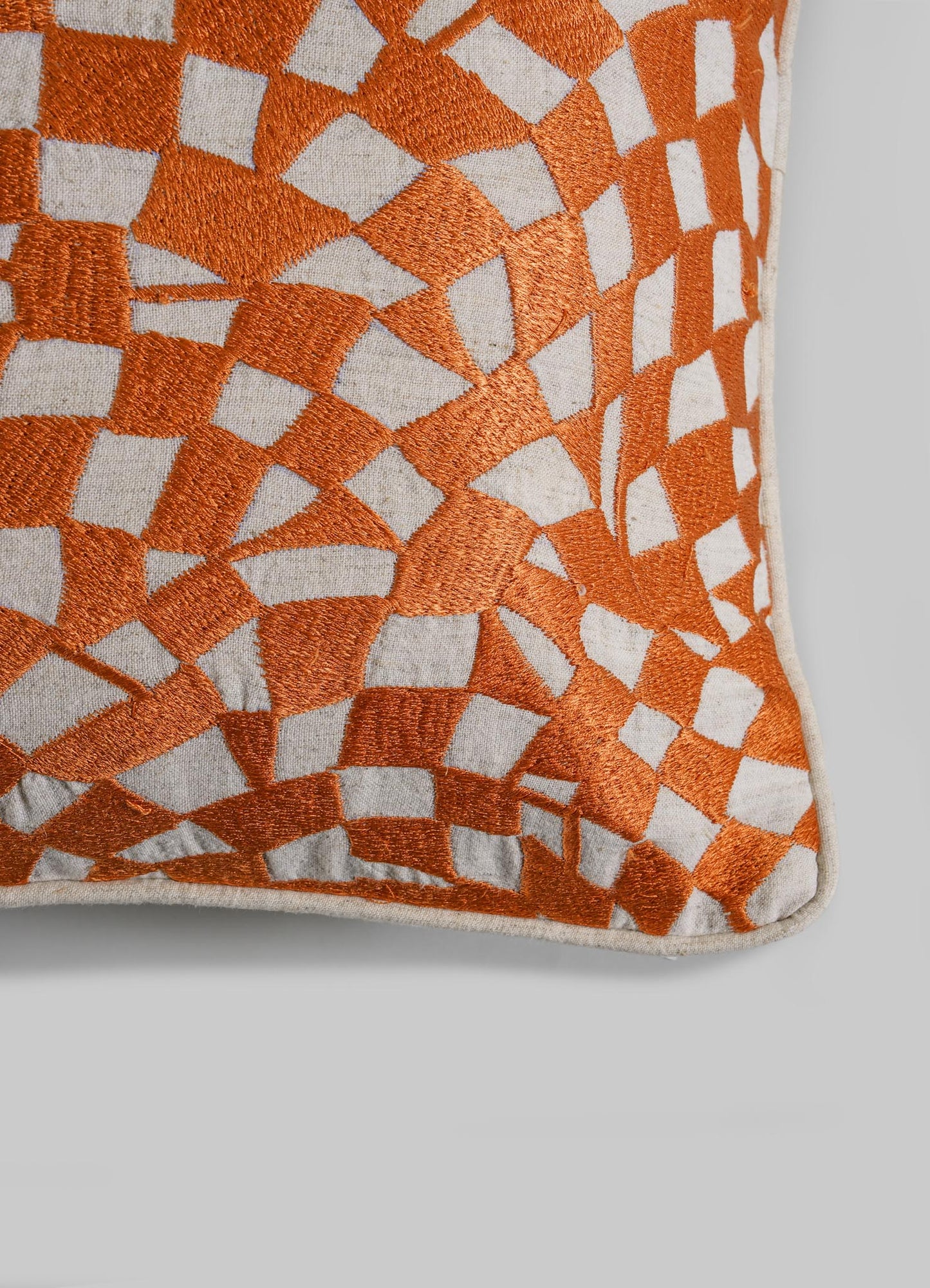 The Viya Dreamscape Orange Embroidered Checks Cushion Cover 18"x18" features an abstract geometric orange and white pattern on a light gray background, inspired by embroidered textile motifs and resembling irregular mosaic shapes.