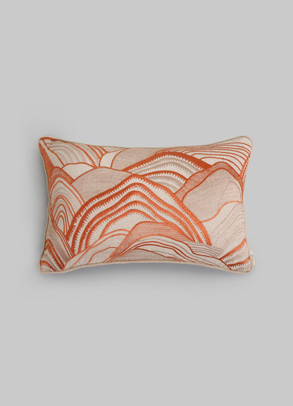 The Viya Dreamscape Orange Embroidered Mounds Cushion Cover (12"x18") features textured, wave-like embroidery in orange, rust, and cream on a light background, shown against a plain gray backdrop.