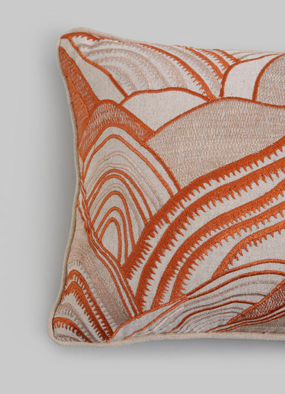 The Viya Dreamscape Orange Embroidered Mounds Cushion Cover 12"x18" features cream fabric with an abstract orange and beige embroidered pattern of curved, layered lines on a plain light grey background.