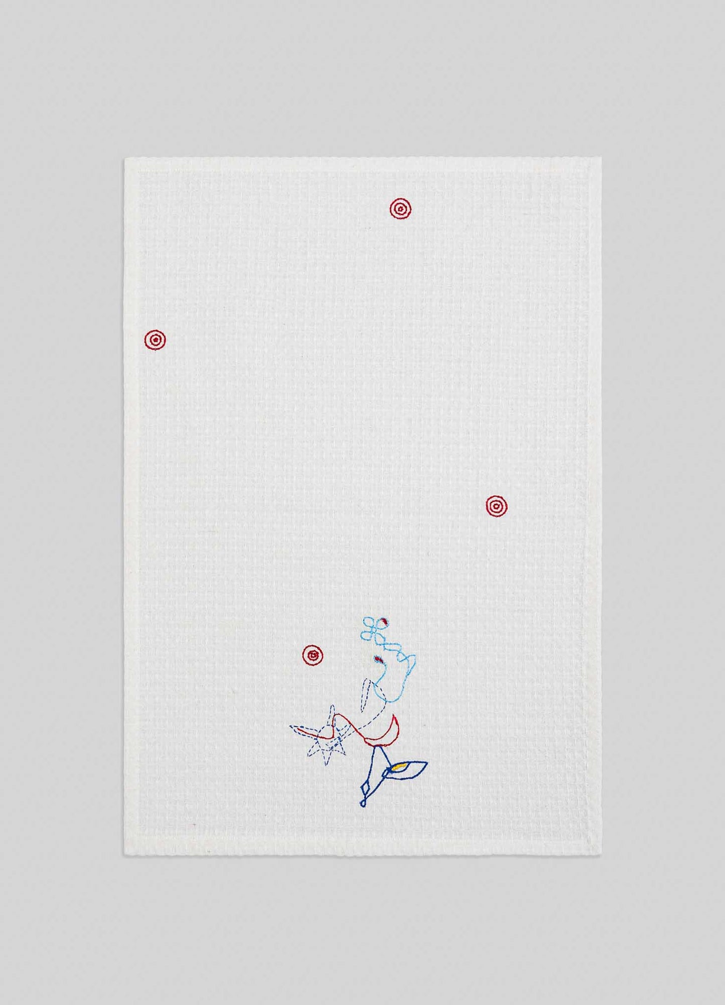The Viya Evil Eye Hand Embroidered Ecru Hand Towels (Set of 2) feature a white textured finish with small red target-like Nazar motifs and a blue and red abstract line art figure near the bottom, set against a light gray background.