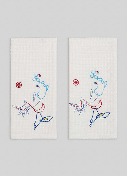 The Evil Eye Hand Embroidered Ecru Hand Towels - Set of 2 by Viya feature colorful abstract embroidery and playful star designs inspired by the Nazar motif, adding a protective totem touch against their light gray background.