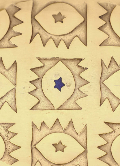 The VIYA Evil Eye Trinket Tray Large features a gold surface engraved with repeating eye motifs, each with a star center; one eye has a blue star like the classic evil eye, while others display brown stars.