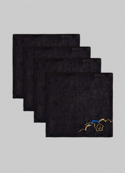 The Viya Gajasimha Hand Embroidered Black & Gold Cocktail Napkins (Set of 4) are neatly stacked, each featuring a gold embroidery inspired by ancient Indian art, set against a light gray background.