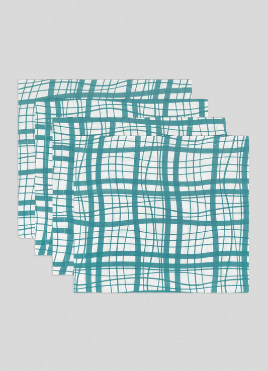The Viya Madras Check Aqua Napkins - Set of 4 features folded fabric napkins with a teal crisscross grid on white, evoking classic madras checks and shown arranged in a staggered stack against a light grey background.