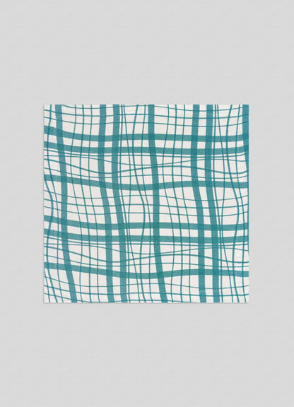 The Viya Madras Check Aqua Napkins – Set of 4 features teal and green madras checks on white fabric, shown flat on a light grey surface—perfect for bringing classic charm to your modern collection.