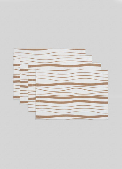 The Viya Madras Check Beige Placemats, set of 4, feature a white base with wavy brown lines inspired by contemporary Indian textiles, shown stacked in a staggered arrangement on a light gray surface.