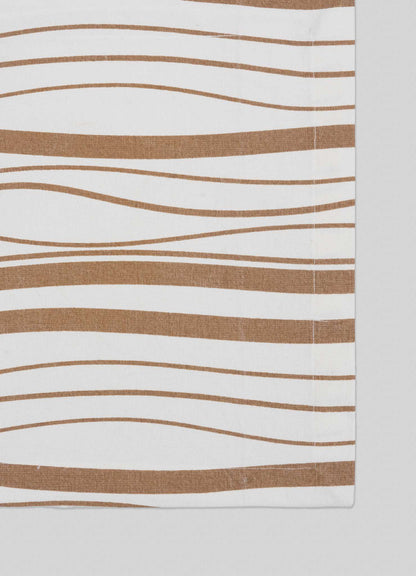 The Madras Check Beige Placemats by Viya feature abstract, wavy brown stripes on white fabric, giving a modern edge to Indian textiles. Set of 4 placemats; photo shows the right edge, indicating partial view or fold.