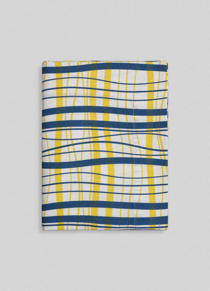 The Viya Madras Check Blue & Yellow Table Cloth features bold blue, yellow, and white checks with wavy lines on a light gray dotted background—an ideal choice for adding contemporary flair to classic Indian subcontinent designs.