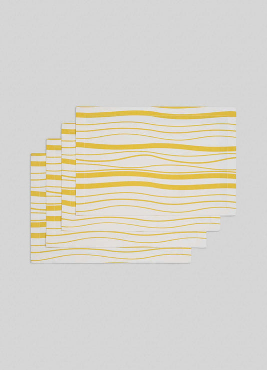 The Viya Madras Check Yellow Placemats (Set of 4) feature a white background with wavy yellow lines, blending contemporary style with hints of Indian textile design. Shown stacked on a light gray surface.