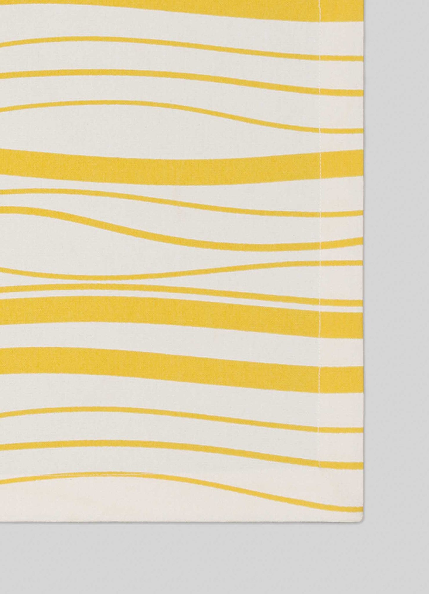 A close-up of Viya's Madras Check Yellow Placemats – Set of 4, showcasing Indian-inspired textile design with horizontal yellow wavy lines on an off-white background and visible edge stitching.