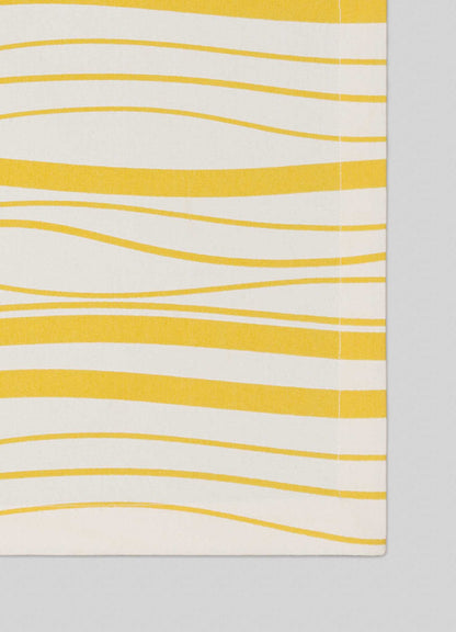 A close-up of Viya's Madras Check Yellow Placemats – Set of 4, showcasing Indian-inspired textile design with horizontal yellow wavy lines on an off-white background and visible edge stitching.