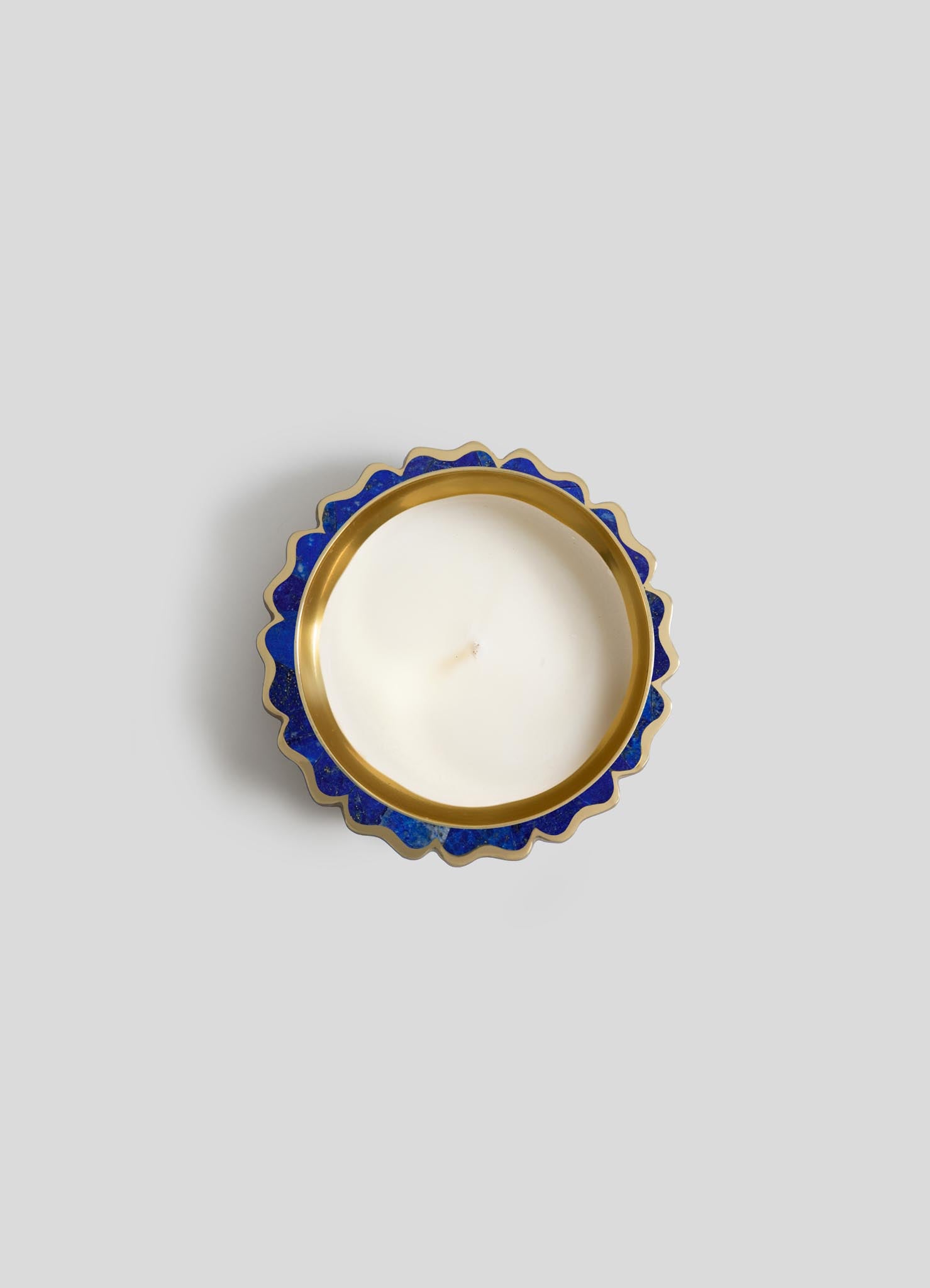 The Mystical Marigold Blue Scented Candle Diya Small - Set of 2 by Viya features white candles with centered wicks in round, gold-trimmed blue holders with scalloped edges, inspired by traditional Indian metalwork.