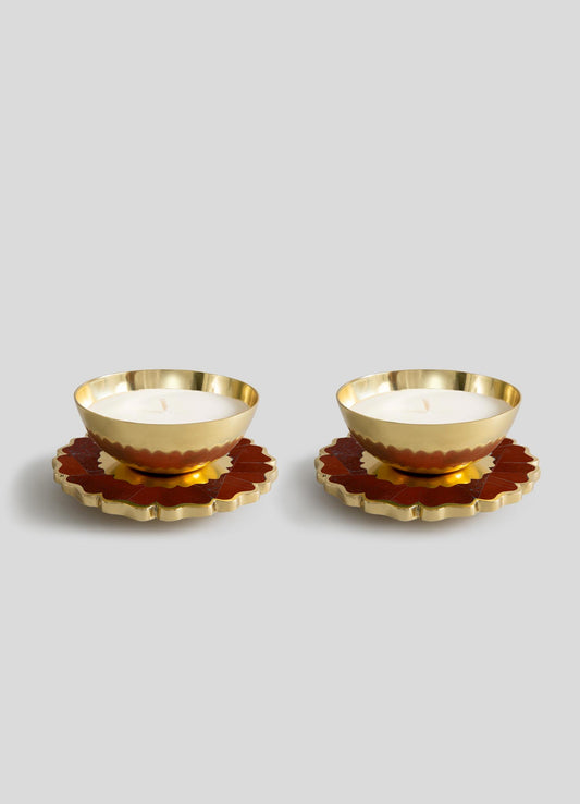 The Mystical Marigold Red - Scented Candle Diya Small Set by Viya features two gold-toned round holders with scalloped edges, each with a white candle, presented on matching coasters against a plain gray backdrop.