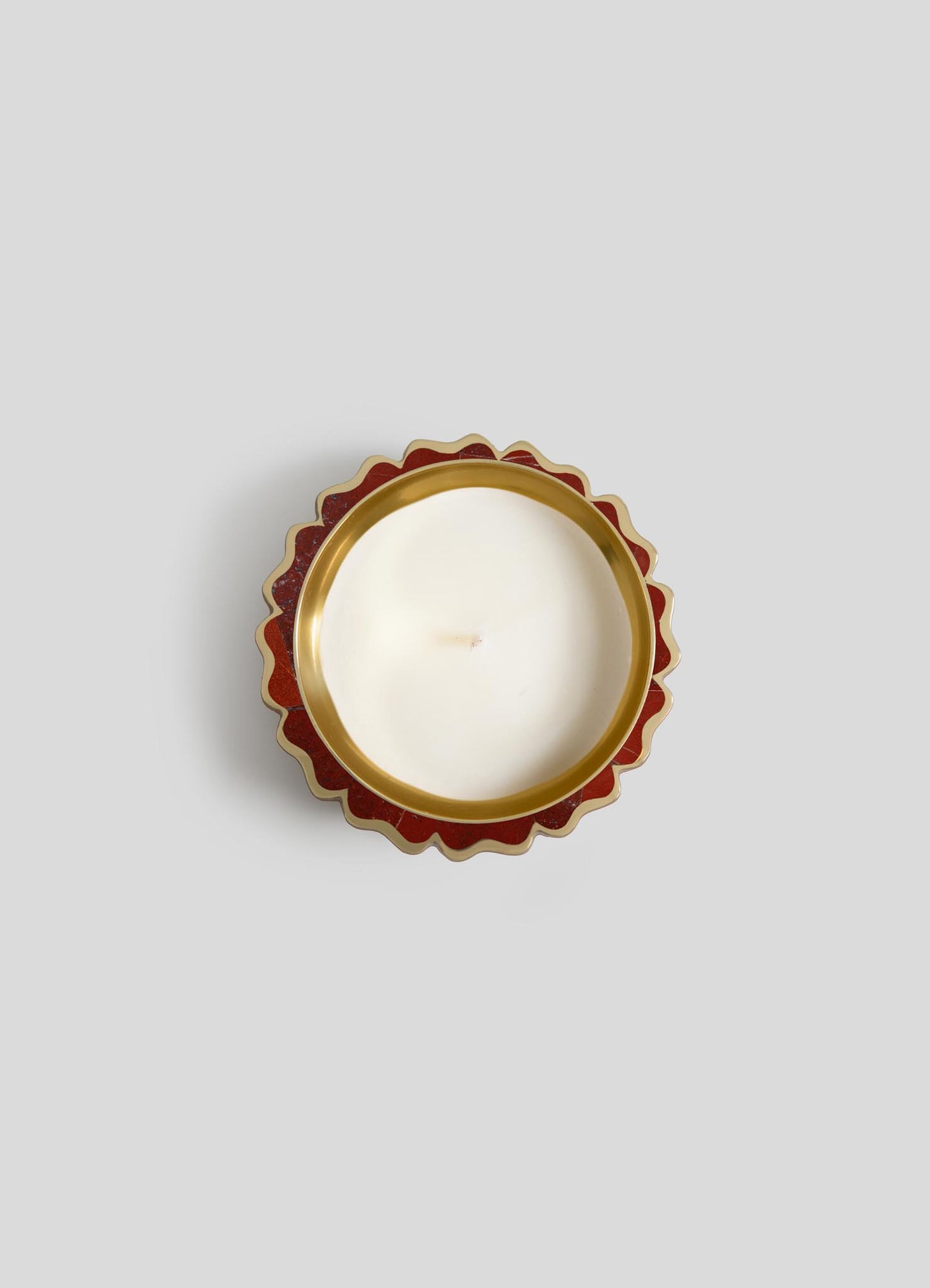 A top-down view of Viya's Mystical Marigold Red - Scented Candle Diya Small (Set of 2) in a white round tin with scalloped red and gold edge, inspired by ancient metalworking, set against a plain light gray background.