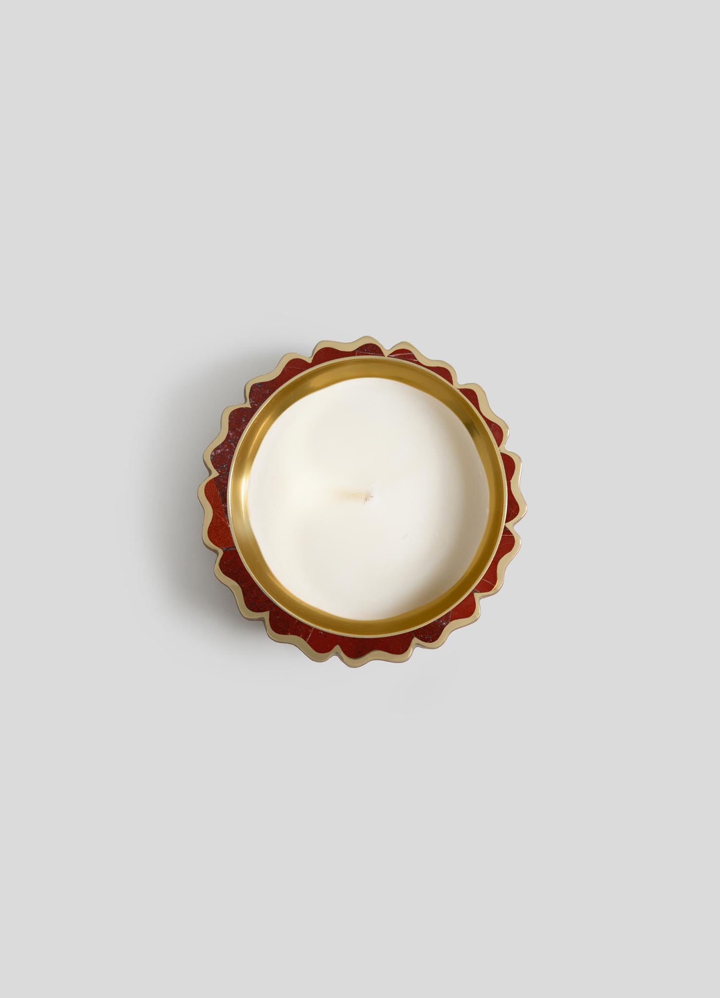 A top-down view of Viya's Mystical Marigold Red - Scented Candle Diya Small (Set of 2) in a white round tin with scalloped red and gold edge, inspired by ancient metalworking, set against a plain light gray background.