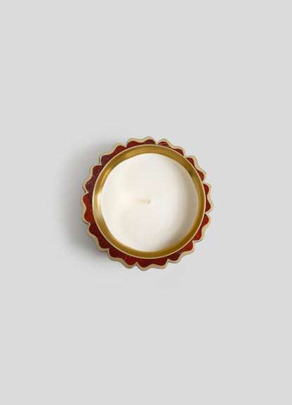 A top-down view of Viya's Mystical Marigold Red - Scented Candle Diya Small (Set of 2) in a white round tin with scalloped red and gold edge, inspired by ancient metalworking, set against a plain light gray background.