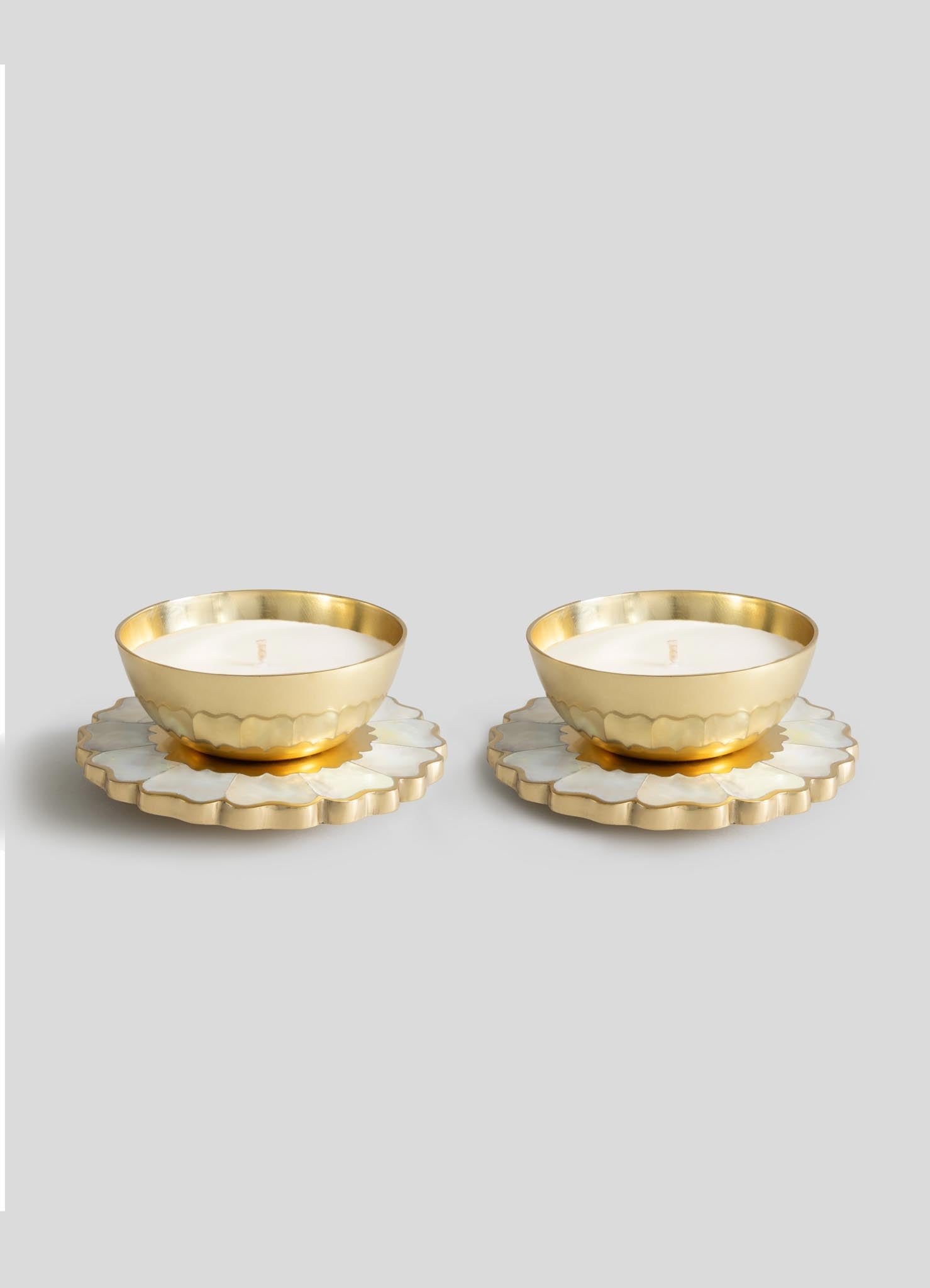 The Viya Mystical Marigold White Scented Candle Diya Small Set of 2 features gold-toned tealights in round holders on white and gold floral bases, showcasing modern heirloom charm inspired by ancient metalwork.