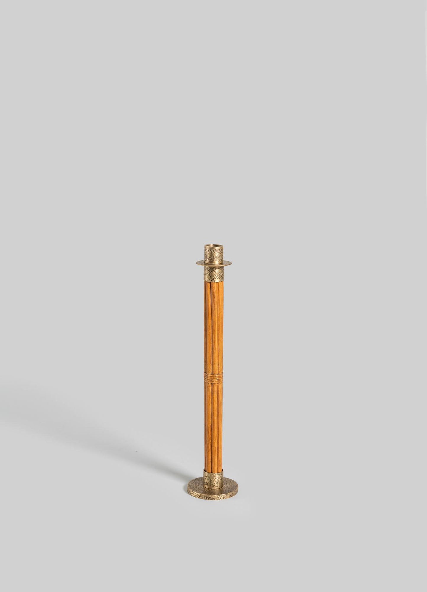 The VIYA Namsai Candle Holder Large features a gold metallic base and top with brass accents, and a sleek wooden pole, standing upright against a plain light gray background.