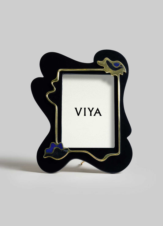 VIYA’s Nazar Black Photo Frame features an abstract black shape with gold outlining and blue accents, standing upright like a protective totem. "VIYA" is printed on a card inside, set against a plain light gray background.