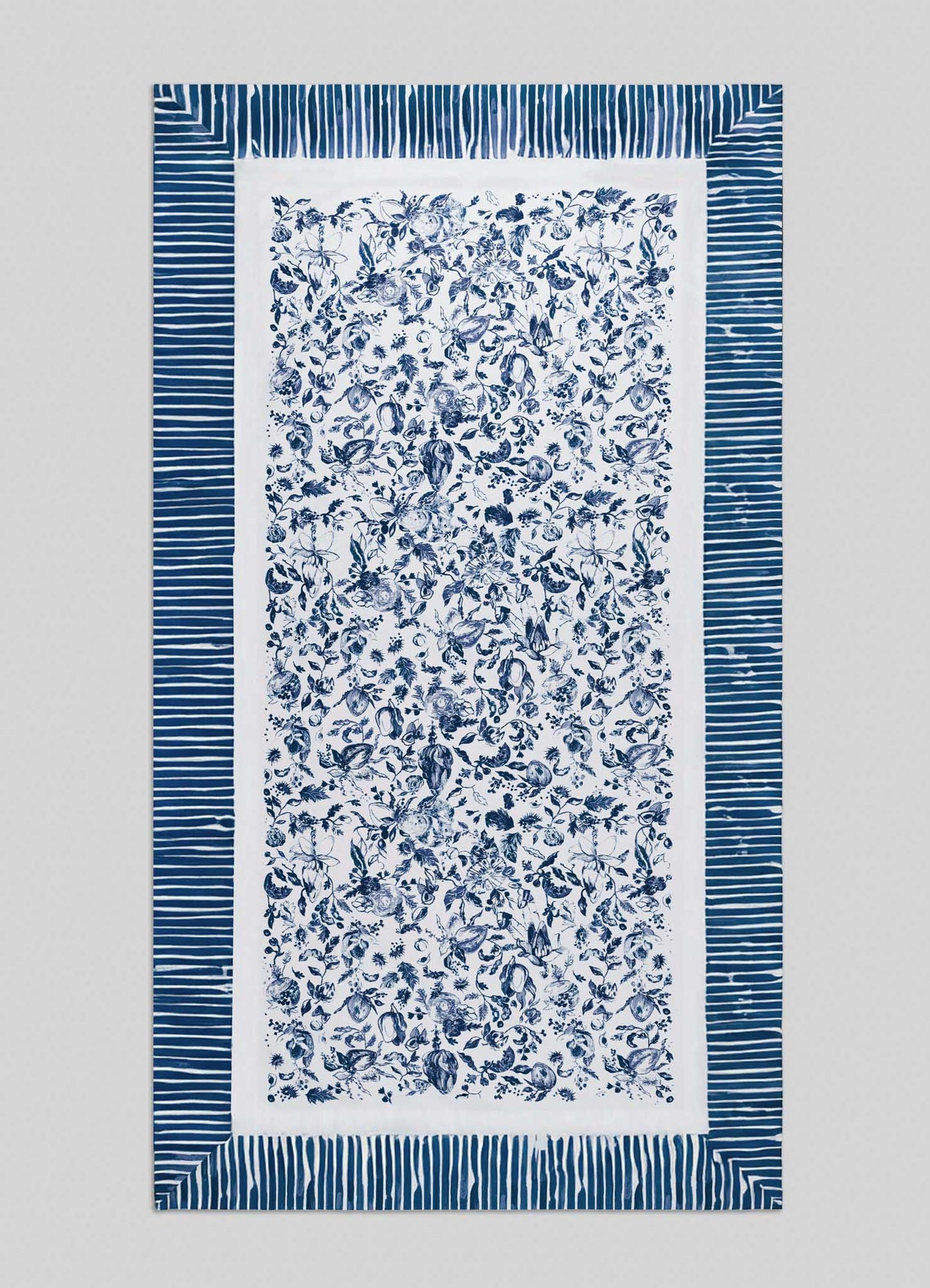 The Orchard Blue Table Cloth Large by Viya showcases a rectangular white design with a dense navy blue floral center, inspired by Indian orchard motifs, framed by wide blue and white stripes.
