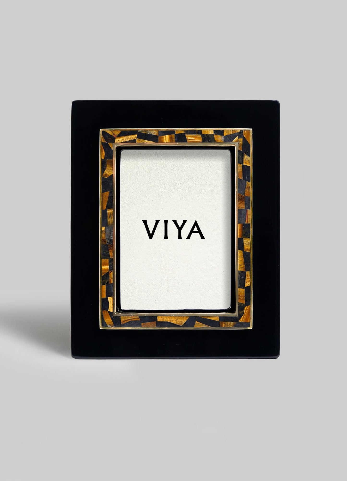 The VIYA Plaza Photo Frame features a glossy black rectangular border with a brown and gold Art Deco mosaic inner edge, and displays a card reading "VIYA," evoking vintage Bombay cinema halls, all set against a plain background.
