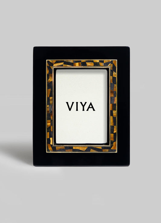 The VIYA Plaza Photo Frame features a glossy black rectangular border with a brown and gold Art Deco mosaic inner edge, and displays a card reading "VIYA," evoking vintage Bombay cinema halls, all set against a plain background.