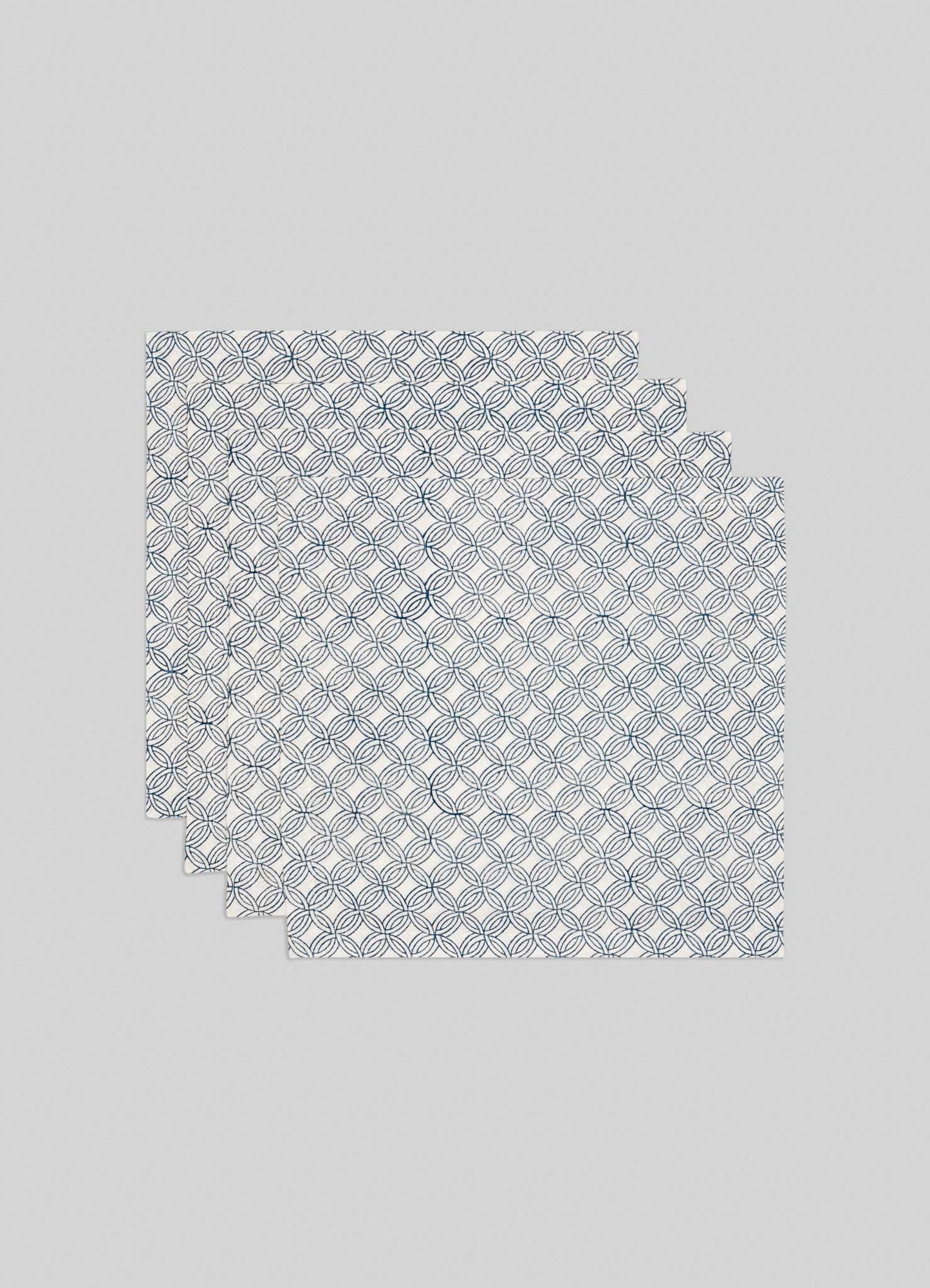 Set of 4 Paigah Navy Napkins by Viya, featuring white cloth with navy blue overlapping circular patterns inspired by Indo-Islamic Hyderabadi architecture. Shown folded in both rectangle and triangle shapes on a light background.