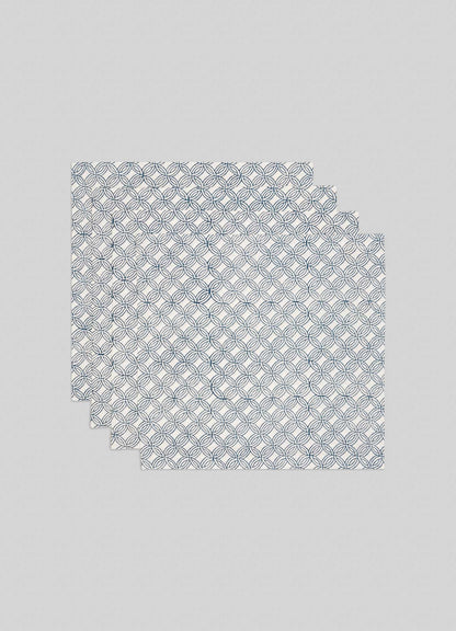 Set of 4 Paigah Navy Napkins by Viya, featuring white cloth with navy blue overlapping circular patterns inspired by Indo-Islamic Hyderabadi architecture. Shown folded in both rectangle and triangle shapes on a light background.