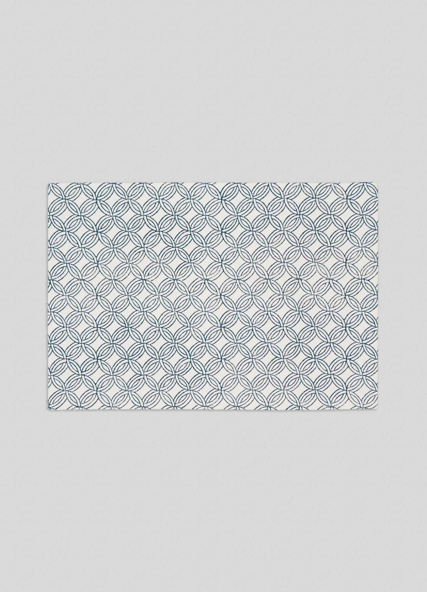 The Viya Paigah Navy Placemats – Set of 4 features a rectangular white design with overlapping blue circles, inspired by Hyderabad's Paigah jaalis, set against a plain light gray background.