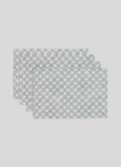 The Viya Paigah Navy Placemats - Set of 4 feature a repeating pattern inspired by Hyderabad’s Indo-Islamic jaalis, with overlapping navy and green circles on white, stacked slightly offset.