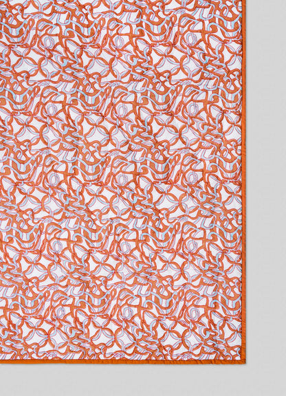 The Viya Paigah Orange & Blue Single Quilt showcases orange and white abstract lattice-inspired patterns with a matching orange border, displayed on a light grey background.