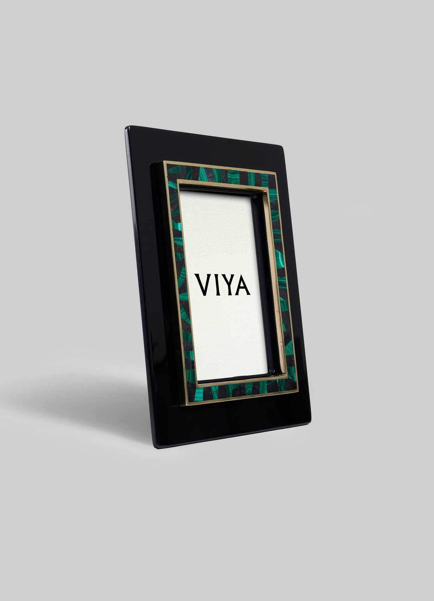 The Rivoli Photo Frame by VIYA features a glossy black rectangular border with a green and gold Art Deco-inspired inner trim. Displayed upright, it evokes vintage Bombay cinema halls against a plain light gray background.