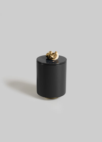 The VIYA Saffron Black Round Container features a sleek black cylindrical design with a smooth finish and a sculptural gold knob lid, inspired by saffron threads, shown against a plain light gray background.