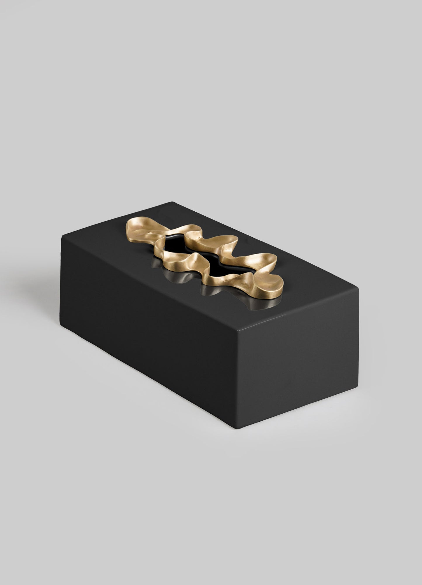 The VIYA Saffron Black Tissue Box Large features a sleek rectangular design in black, topped with a gold wavy abstract detail reminiscent of saffron threads, set against a plain light gray background.