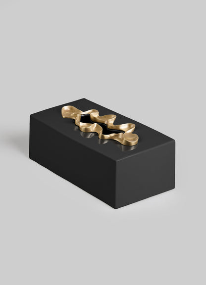 The VIYA Saffron Black Tissue Box Large features a sleek rectangular design in black, topped with a gold wavy abstract detail reminiscent of saffron threads, set against a plain light gray background.