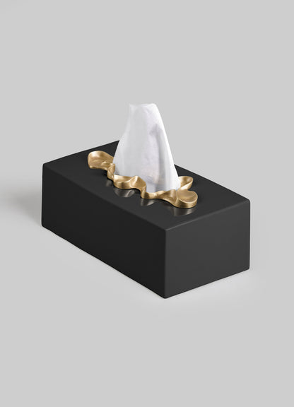 The VIYA Saffron Black Tissue Box Large features a rectangular black design with a gold, wavy-edged opening, holding a single white tissue atop a plain light gray background, evoking the look of contemporary bronzed objects.