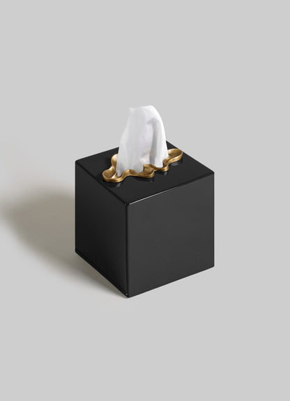 The VIYA Saffron Black Tissue Box Small features a gold-accented top, contemporary style, and displays a white tissue partially pulled out against a plain light grey background.