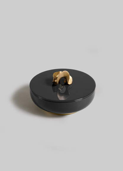 The VIYA Saffron Black Trinket Box Large is a round, black ceramic container with a lid and sculptural gold handle, inspired by the elegance of saffron threads, shown against a plain light gray background.