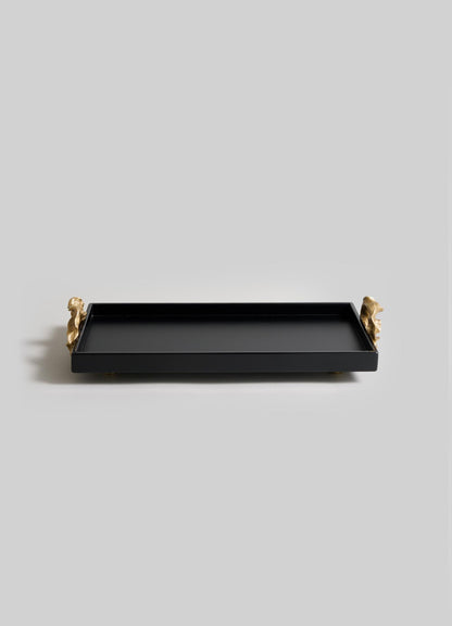 The VIYA Saffron Black Vanity Tray features a rectangular black design with raised edges and gold animal-shaped handles, inspired by ancient Indian medicine, and is beautifully displayed on a light gray background.