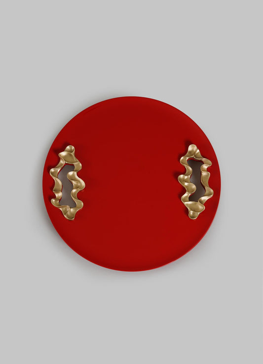 The VIYA Saffron Red Tray Small is a round, bright red serving tray with two wavy gold handles, shown on a plain light gray background.