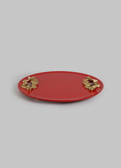 The Saffron Red Tray Small by VIYA features a round, flat design in rich red with smooth edges and two clusters of gold abstract floral accents, inspired by saffron threads, displayed against a plain light gray background.