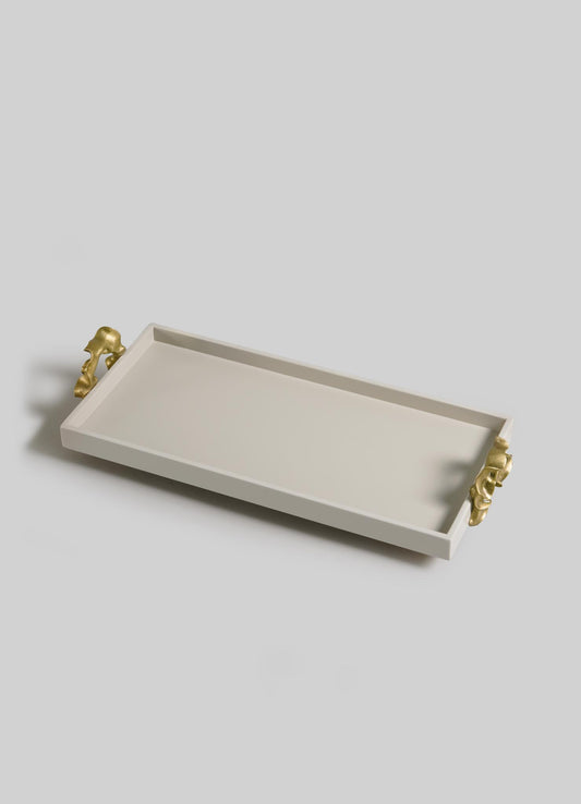 The VIYA Saffron Ecru Vanity Tray is a rectangular white tray with raised edges and two gold animal head handles, evoking contemporary bronzed art, displayed against a light gray background.