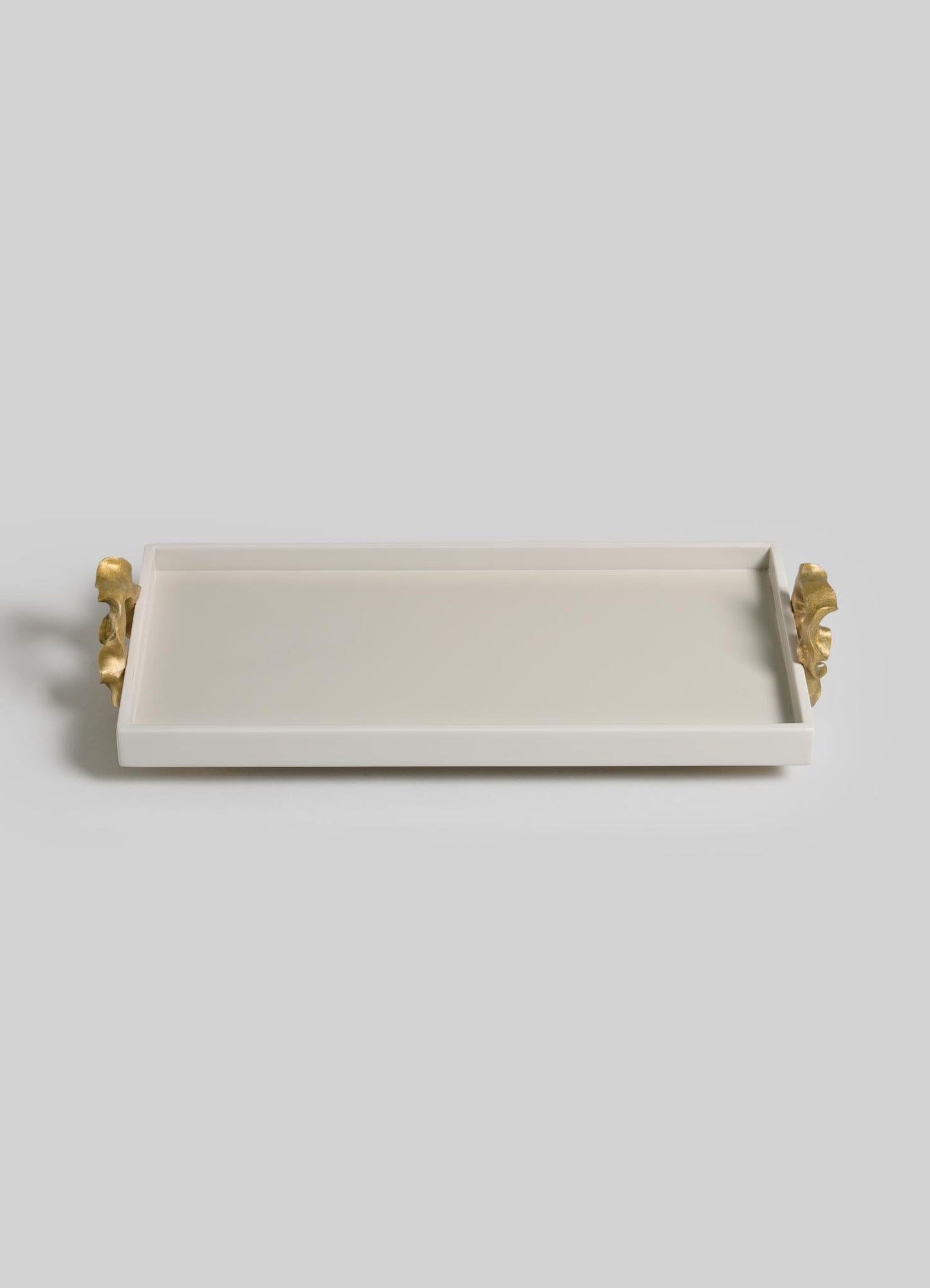 The VIYA Saffron Ecru Vanity Tray features a rectangular white design with raised edges and two gold leaf-shaped handles on each short side, echoing contemporary bronzed décor. Displayed on a light gray background.