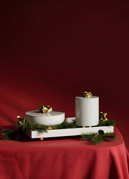 The VIYA Saffron Ecru Trinket Box features elegant white ceramic with gold accents, displayed on a white tray among pine branches and saffron threads, set against a deep red background.