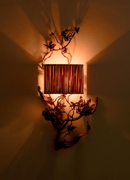 The VIYA Spring In Kashmir Wall Sconce A features a patina finish, cylindrical ribbed shade, and artistic metal branches and leaves—casting warm, dramatic light perfect for elevating your Kashmir-inspired home decor.
