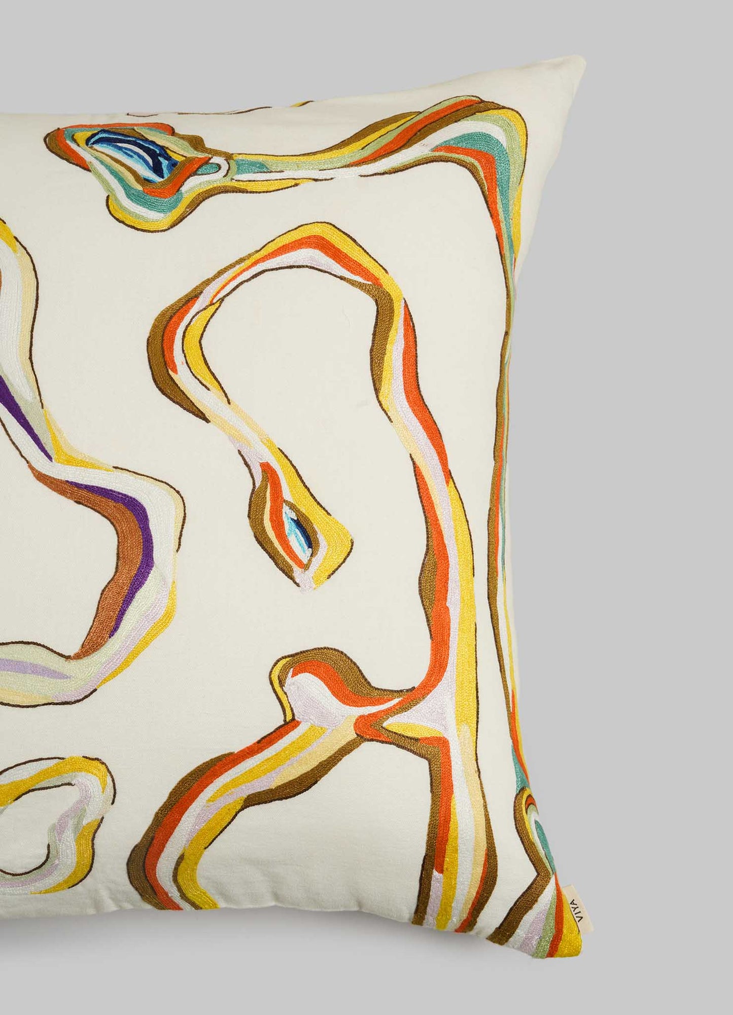 The Viya Tutti Frutti Hand Embroidered Multicolour Cushion Cover 24"x24" features abstract, wavy lines in orange, yellow, brown, and blue on a cream background.