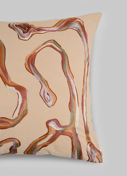 The Viya Tutti Frutti Salmon Pink Cushion Cover (24"x24") features abstract, wavy hand-embroidered lines in brown, rust, pink, green, and white on a beige background—its fluid pattern inspired by Cartier’s Tutti Frutti.